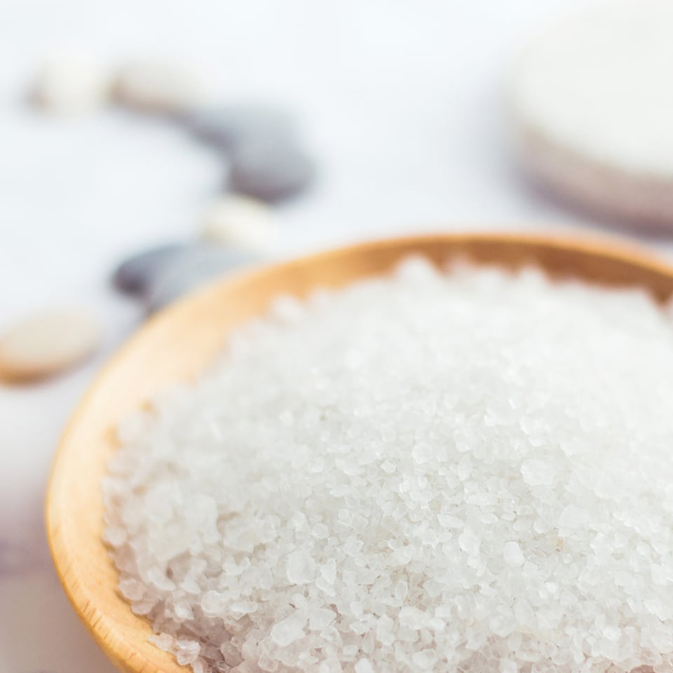 A wooden dish full of Epsom salts with a soft-focus background